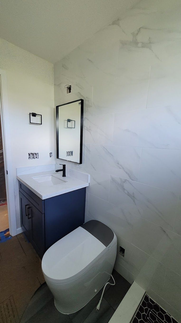 A bathroom with a toilet , sink and mirror.