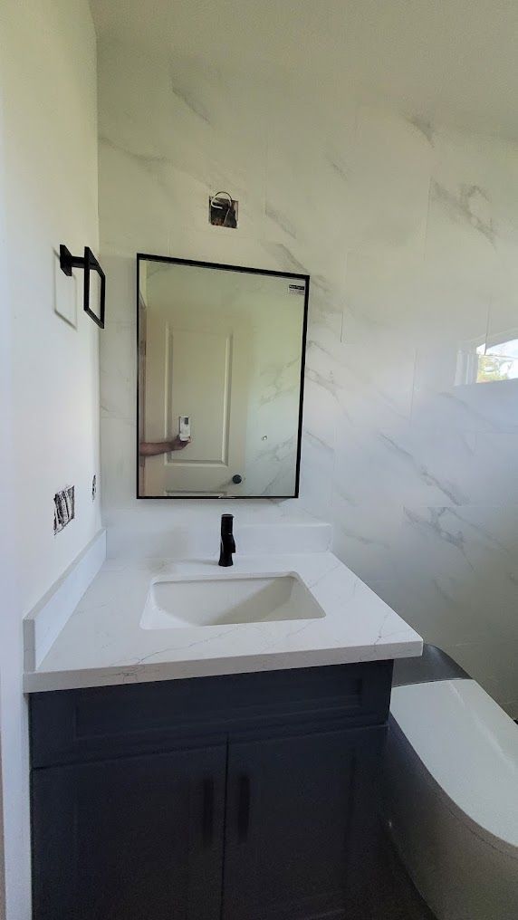 A bathroom with a sink , toilet and mirror.