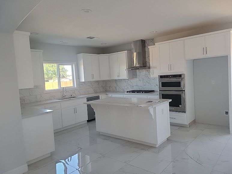 An empty kitchen with white cabinets and stainless steel appliances.