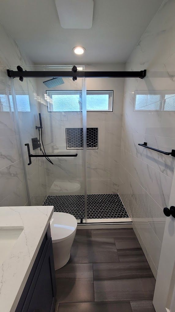 A bathroom with a toilet , sink and shower with a sliding glass door.