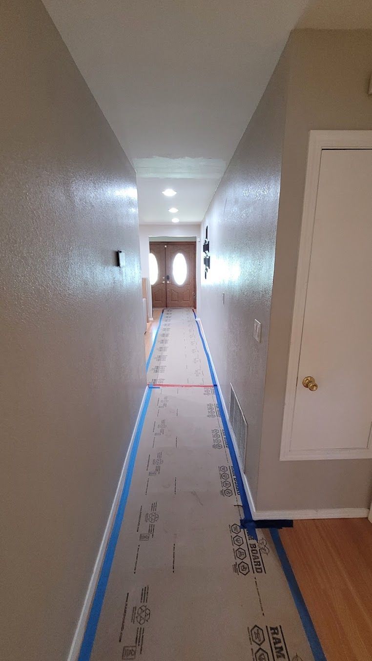 A long hallway with a blue tape on the floor and a door.