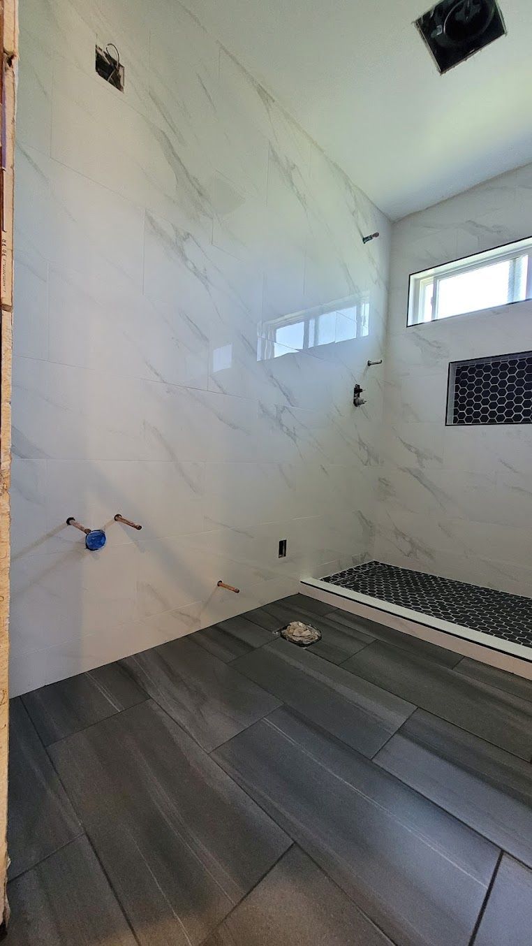 A bathroom with a walk in shower and a window.