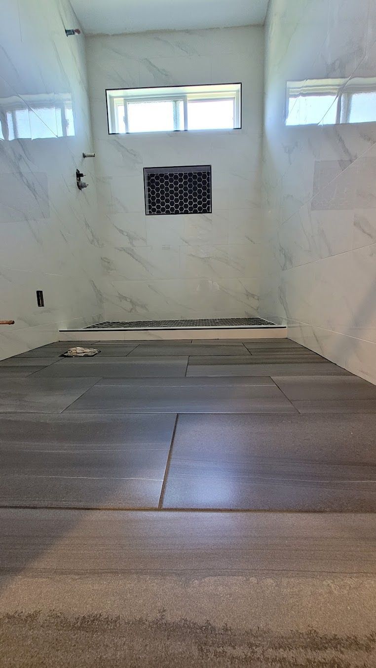 A bathroom with a walk in shower and a window.