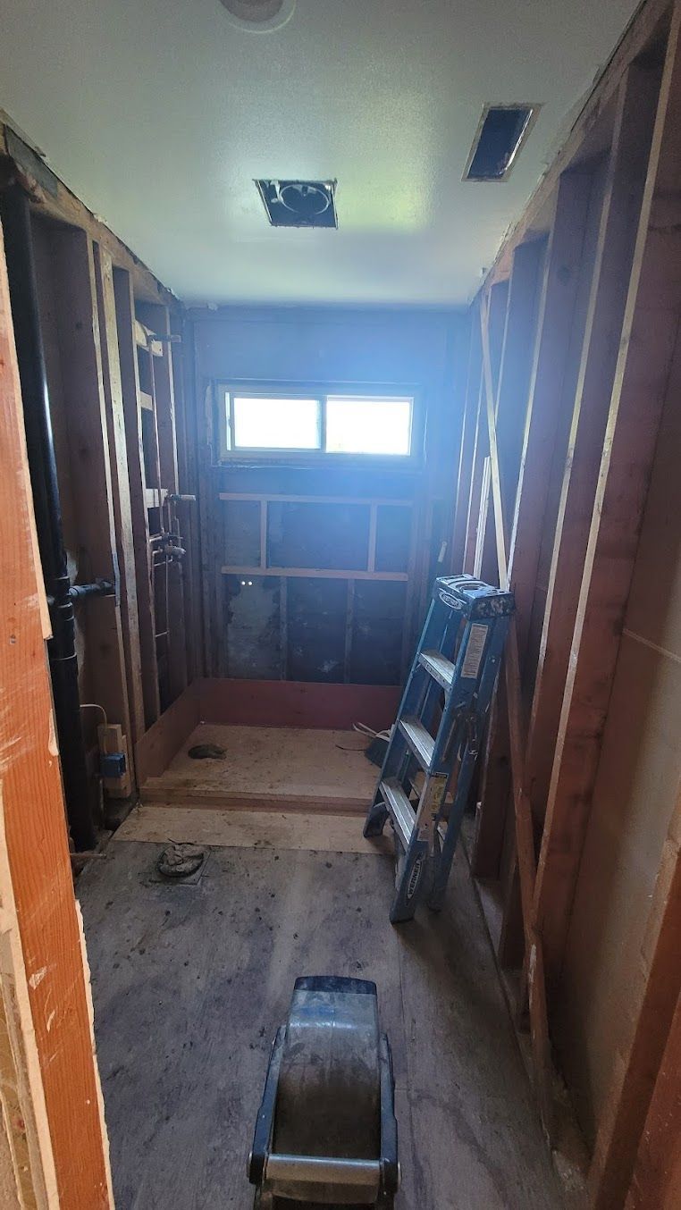 A ladder is sitting on the floor in a room under construction.