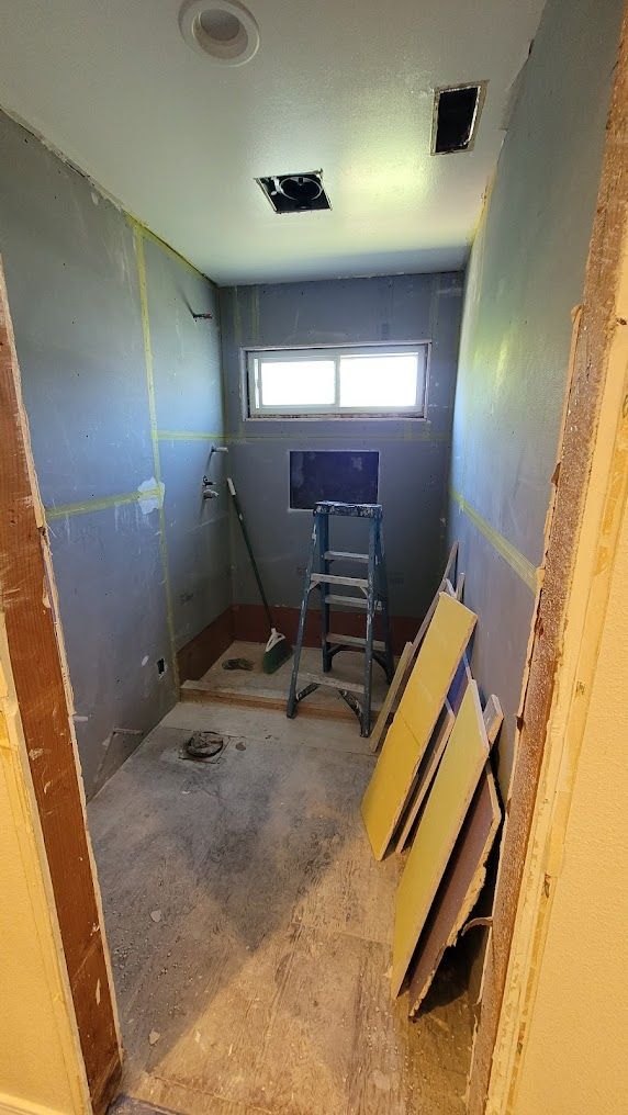 A bathroom under construction with a ladder and a window.