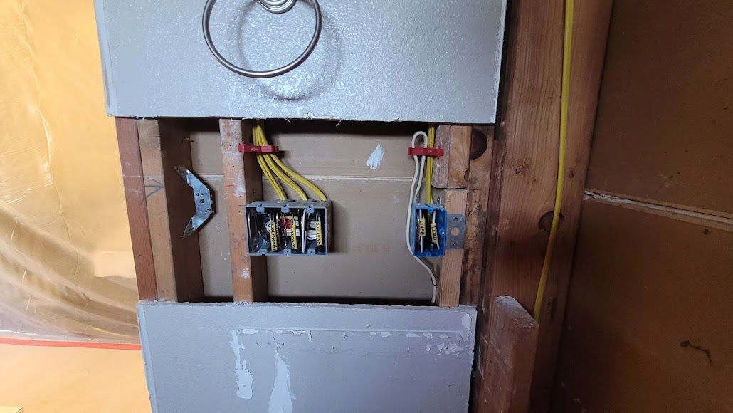 A close up of a wall with electrical wires coming out of it.