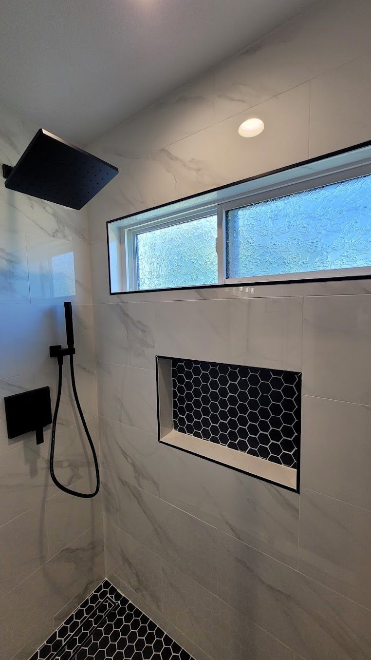 A shower with a window and a shower head.