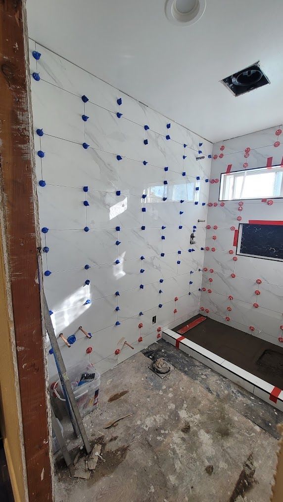 A bathroom under construction with white tiles and a window.