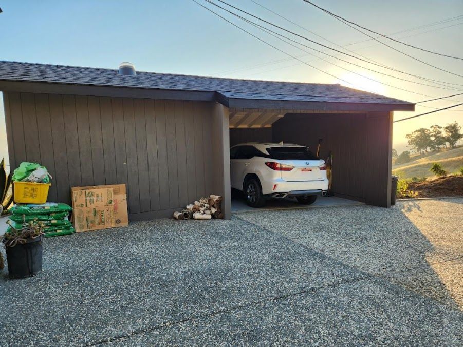 A white car is parked in a garage under a canopy.
