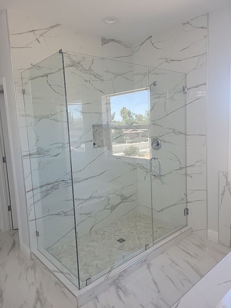 A bathroom with a walk in shower and a window.
