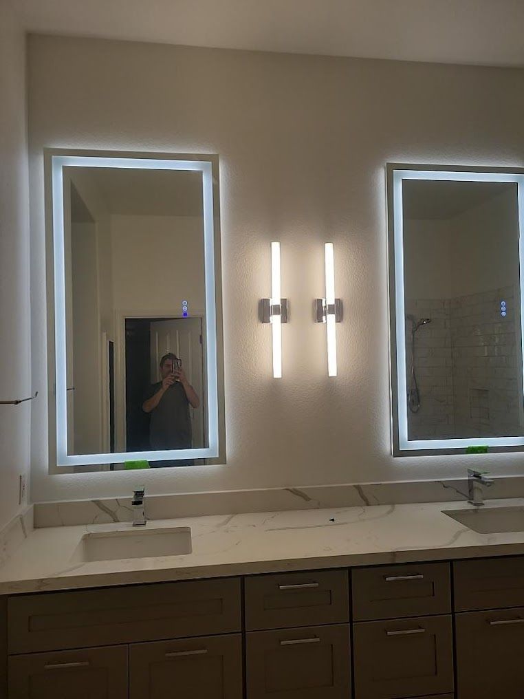 A bathroom with two mirrors and two lights on the wall.