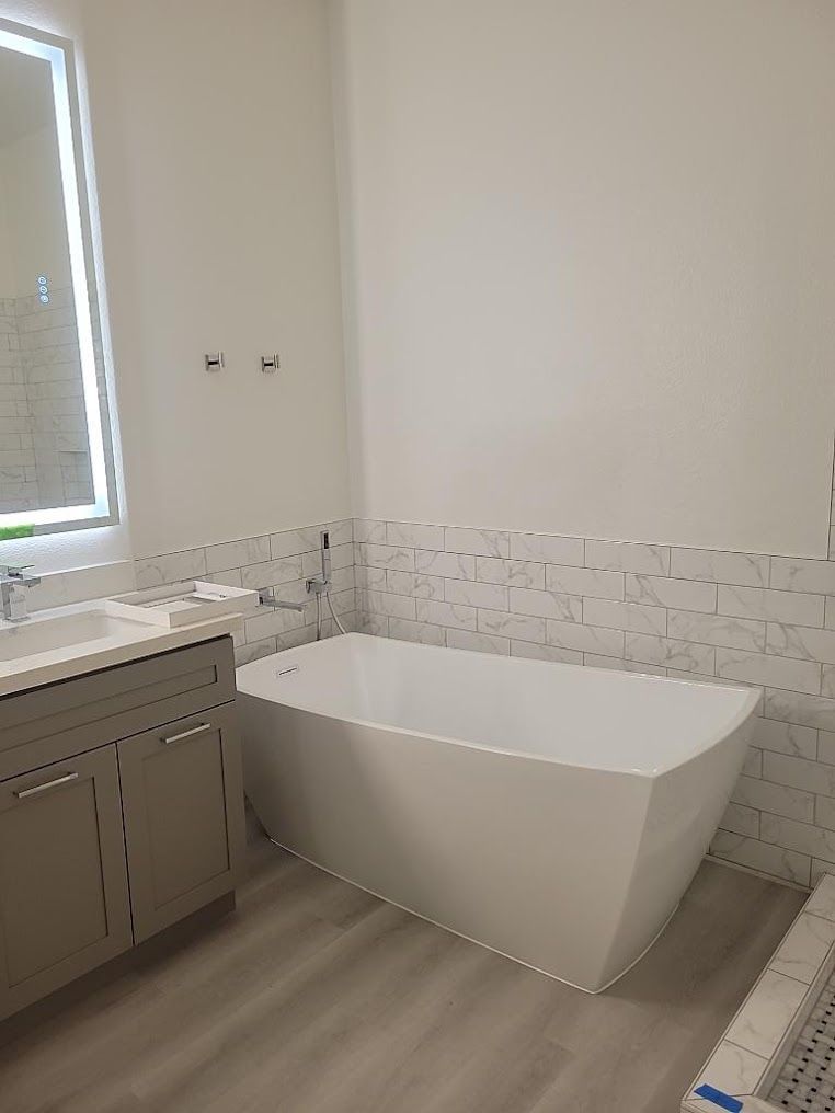A bathroom with a bathtub , sink and mirror.