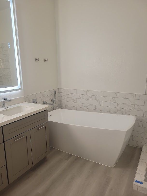 A bathroom with a bathtub , sink and mirror.