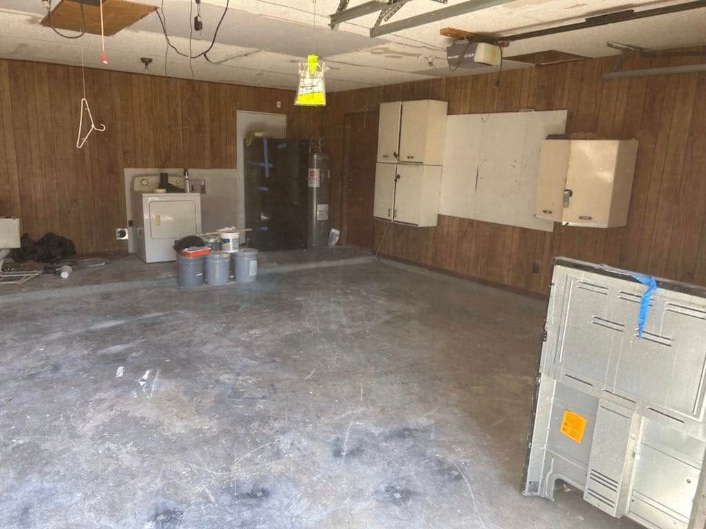 An empty garage with a refrigerator , washer and dryer.