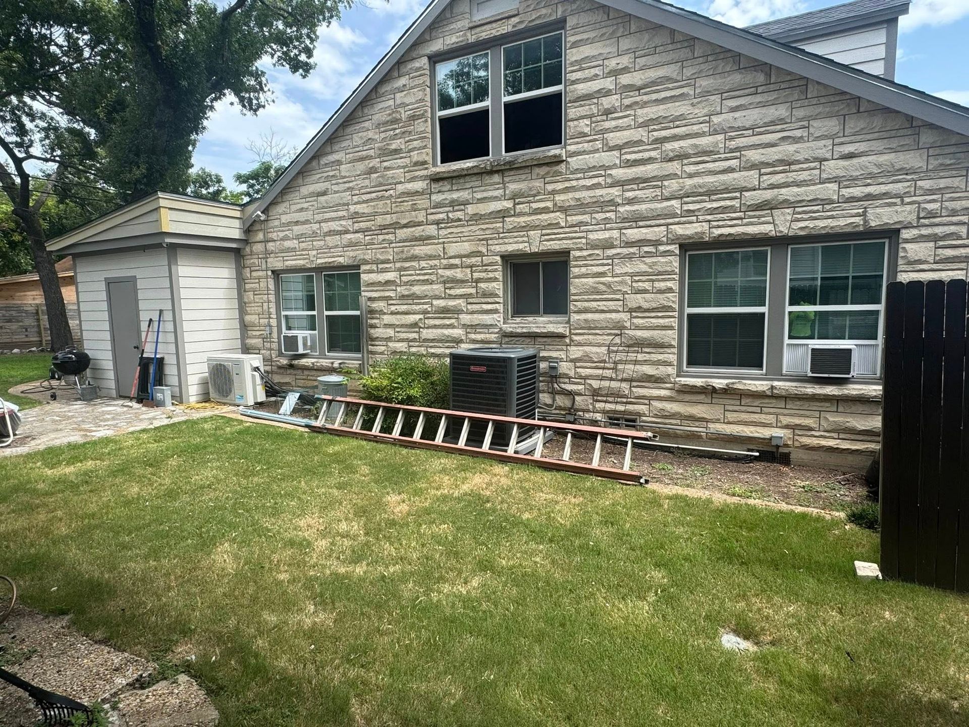 A brick house with a lot of windows and a ladder in front of it.