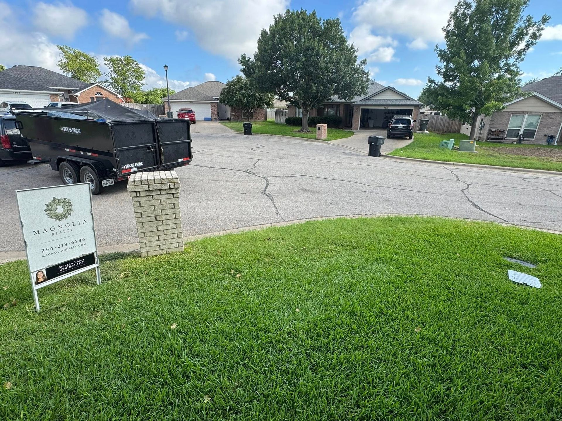 A black truck is parked in front of a house with a sign in the grass.