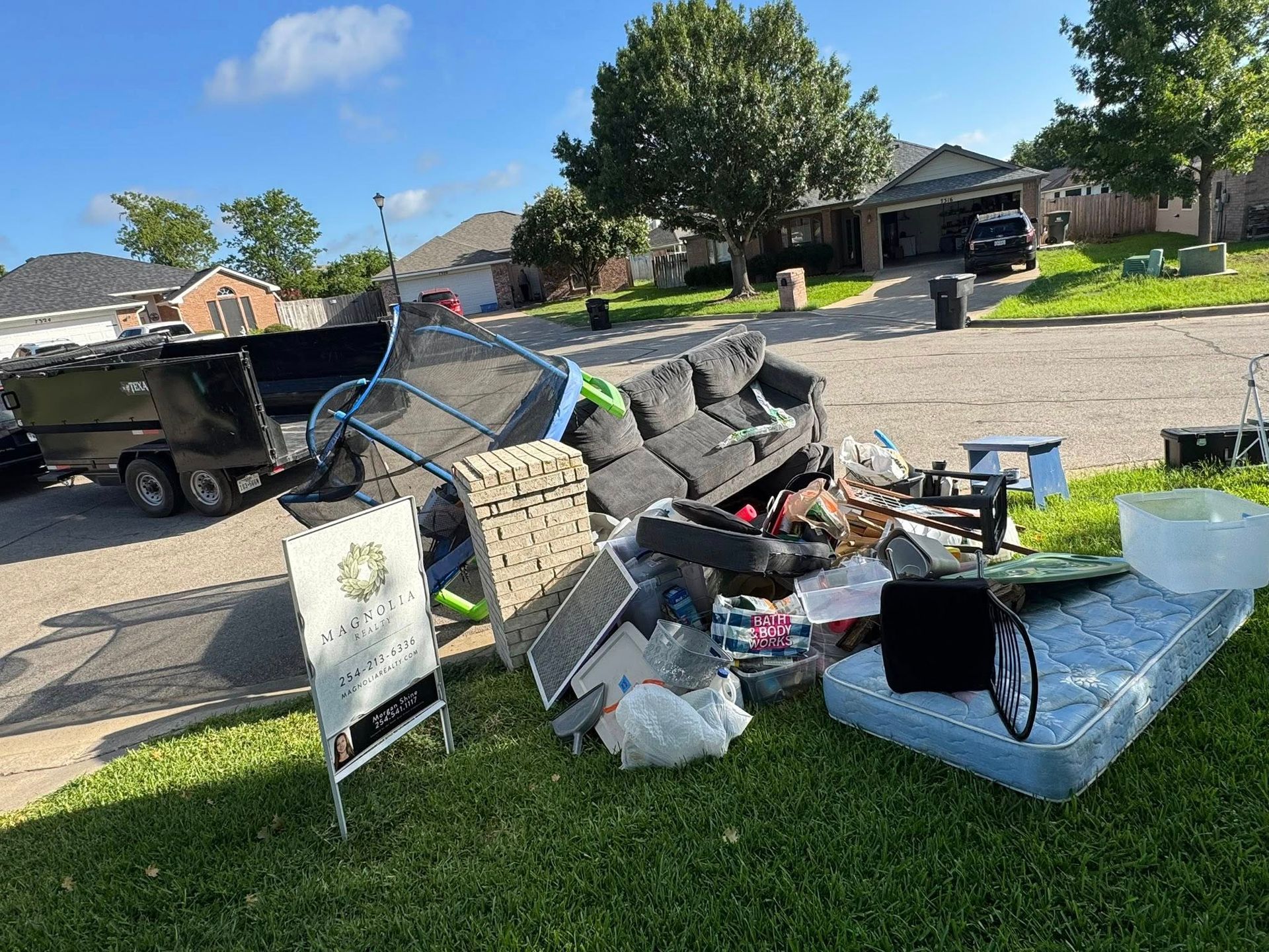A pile of trash is sitting on the grass in front of a house.