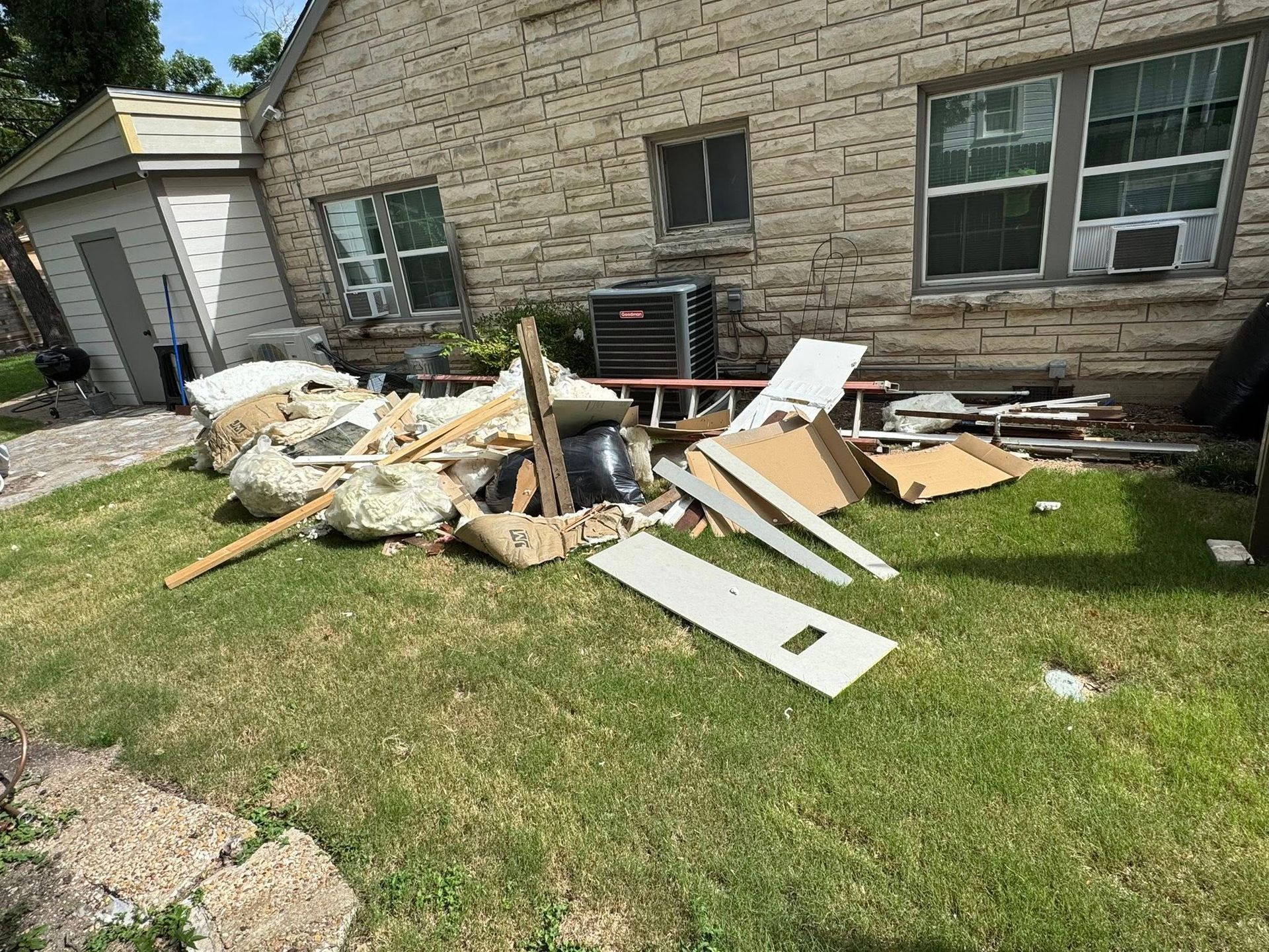 A pile of trash is sitting in front of a brick house.