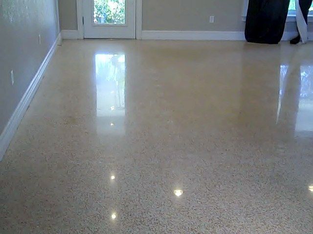 Polished concrete floor reflecting light in a room with a white door and walls