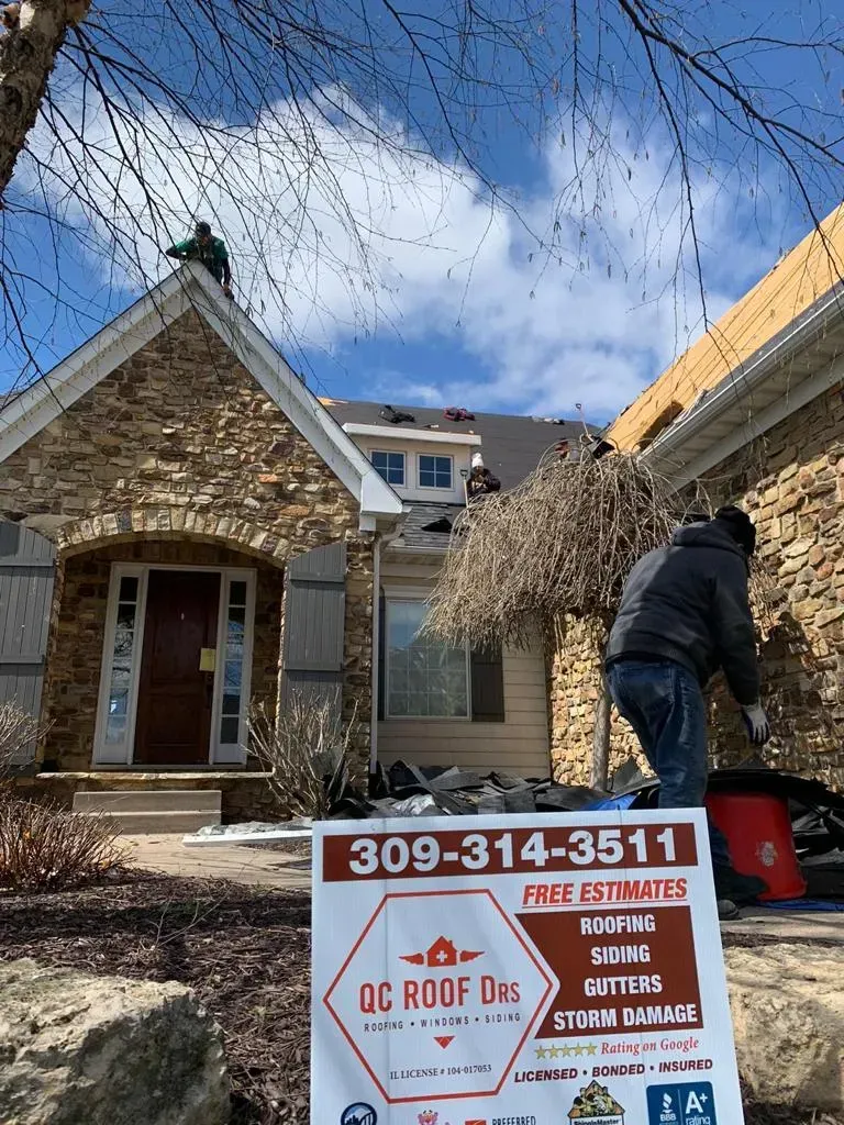 A Man Is Working on The Roof of A House with A Sign in Front of It | Fayetteville, NC | Danny Odom Roofing
