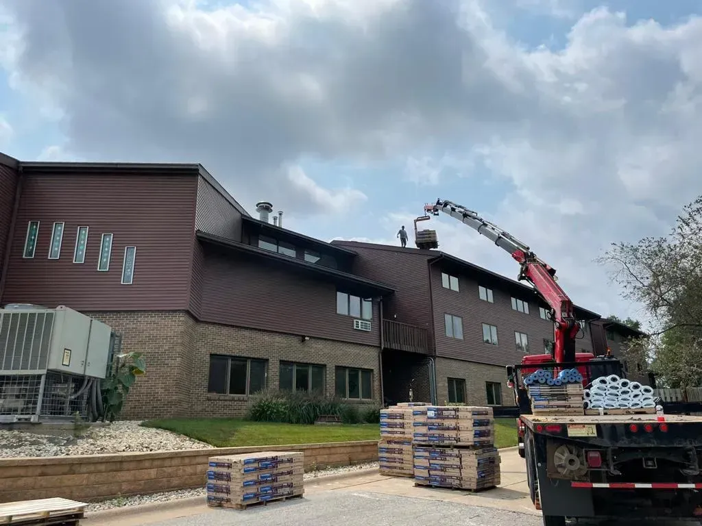 A Truck with A Crane on The Back of It Is Parked in Front of A Building | Fayetteville, NC | Danny Odom Roofing