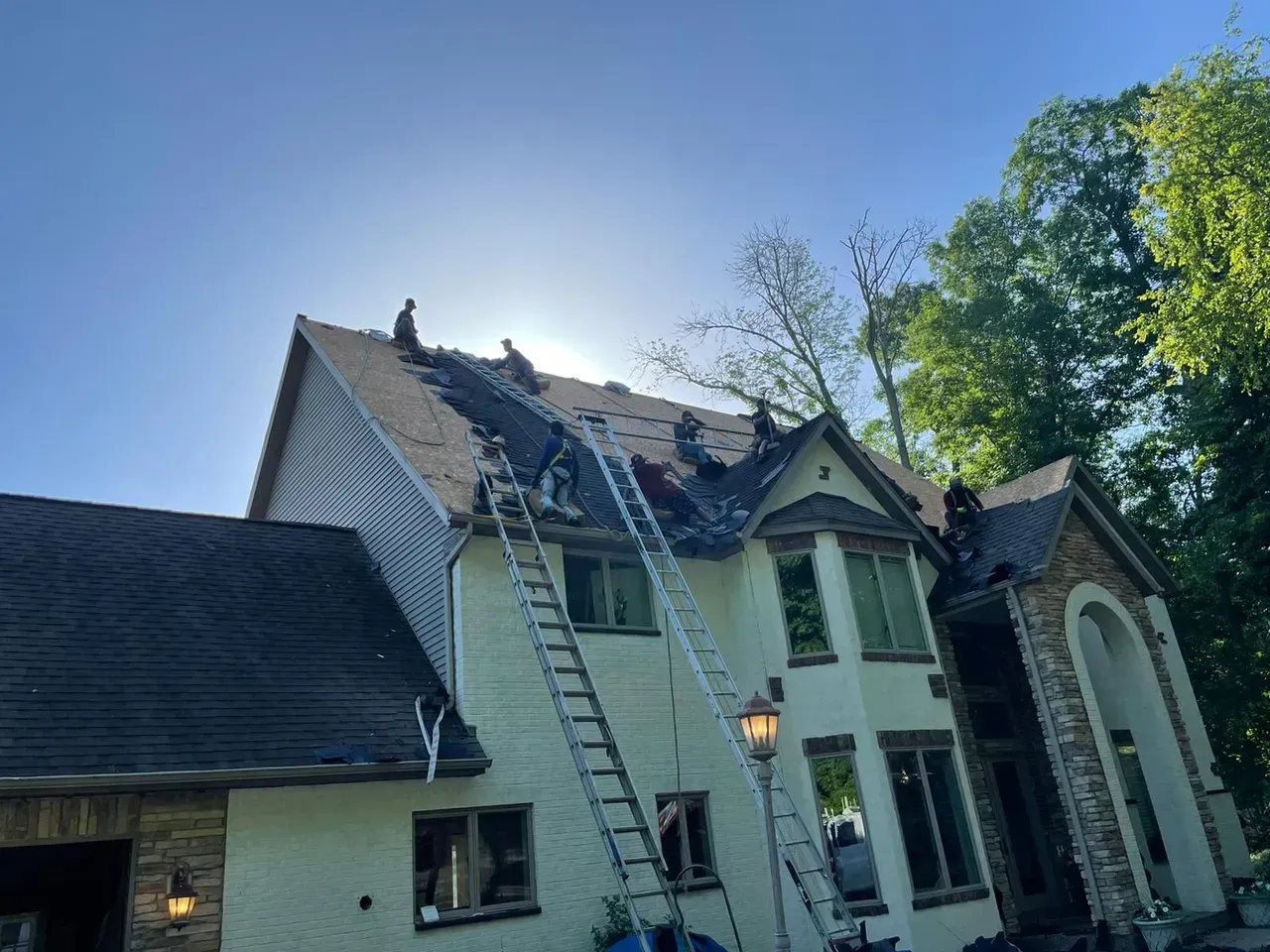 A Large White House with A Ladder on The Roof | Fayetteville, NC | Danny Odom Roofing