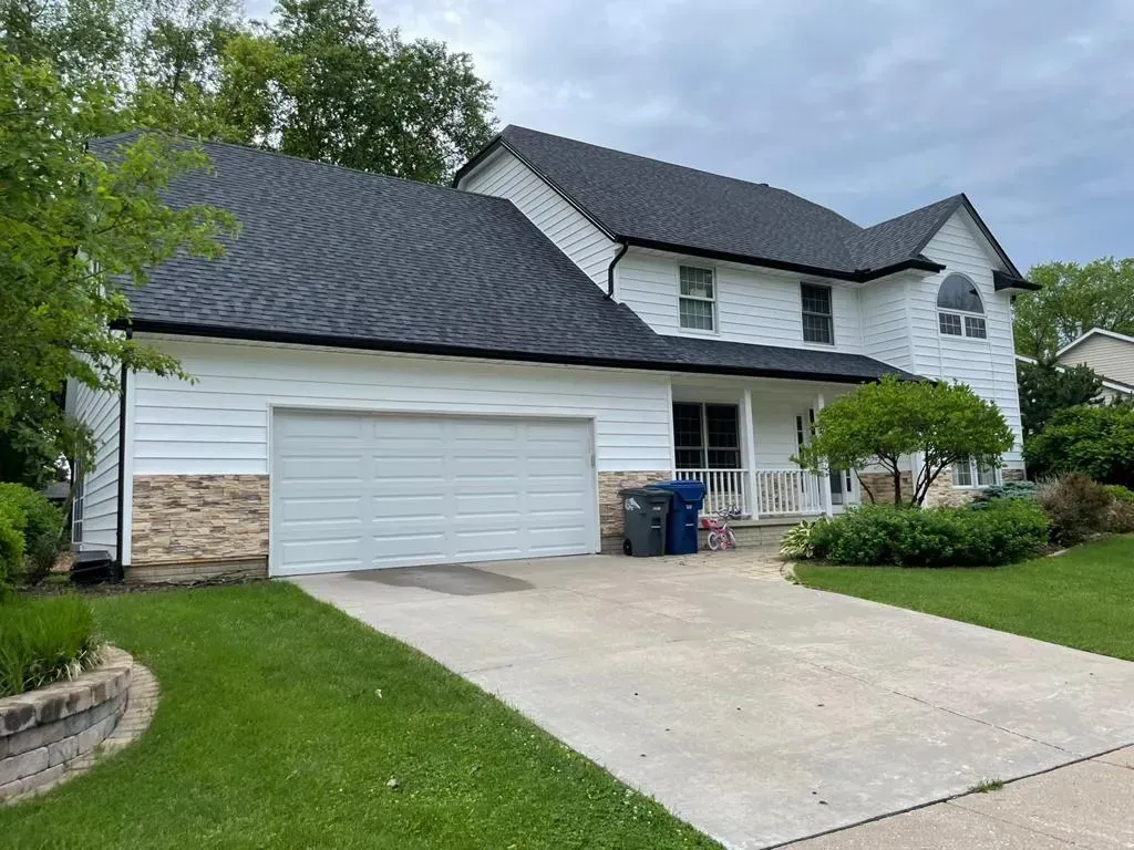 A Large White House with A Black Roof and A White Garage Door | Fayetteville, NC | Danny Odom Roofing
