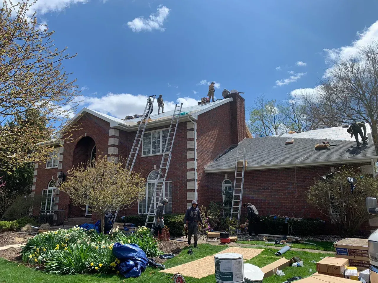 A Group of People Are Working on The Roof of A Brick House | Fayetteville, NC | Danny Odom Roofing