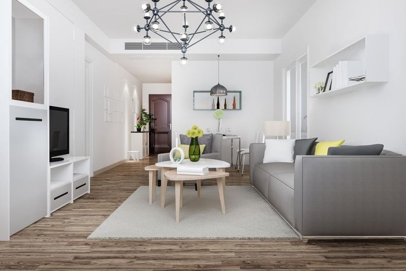 Modern living room with grey sofa, wooden floor, white walls, and a chandelier.