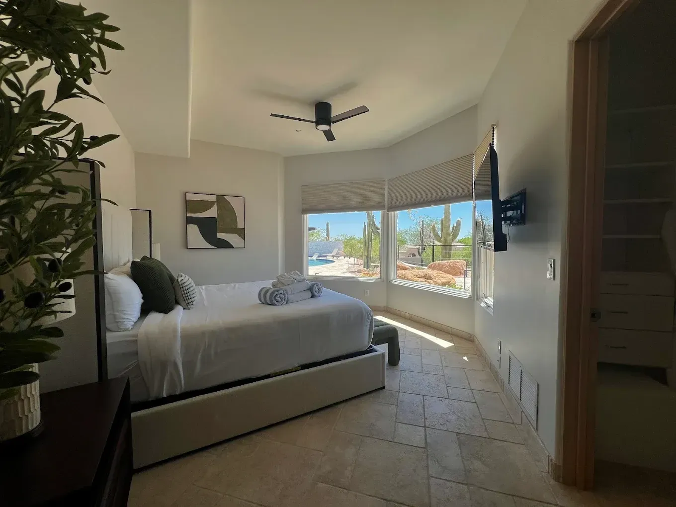 Bedroom with bed, closet, and window overlooking a desert landscape.