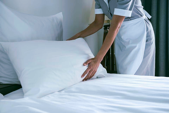 cameriera dell'albergo mentre prepara un letto