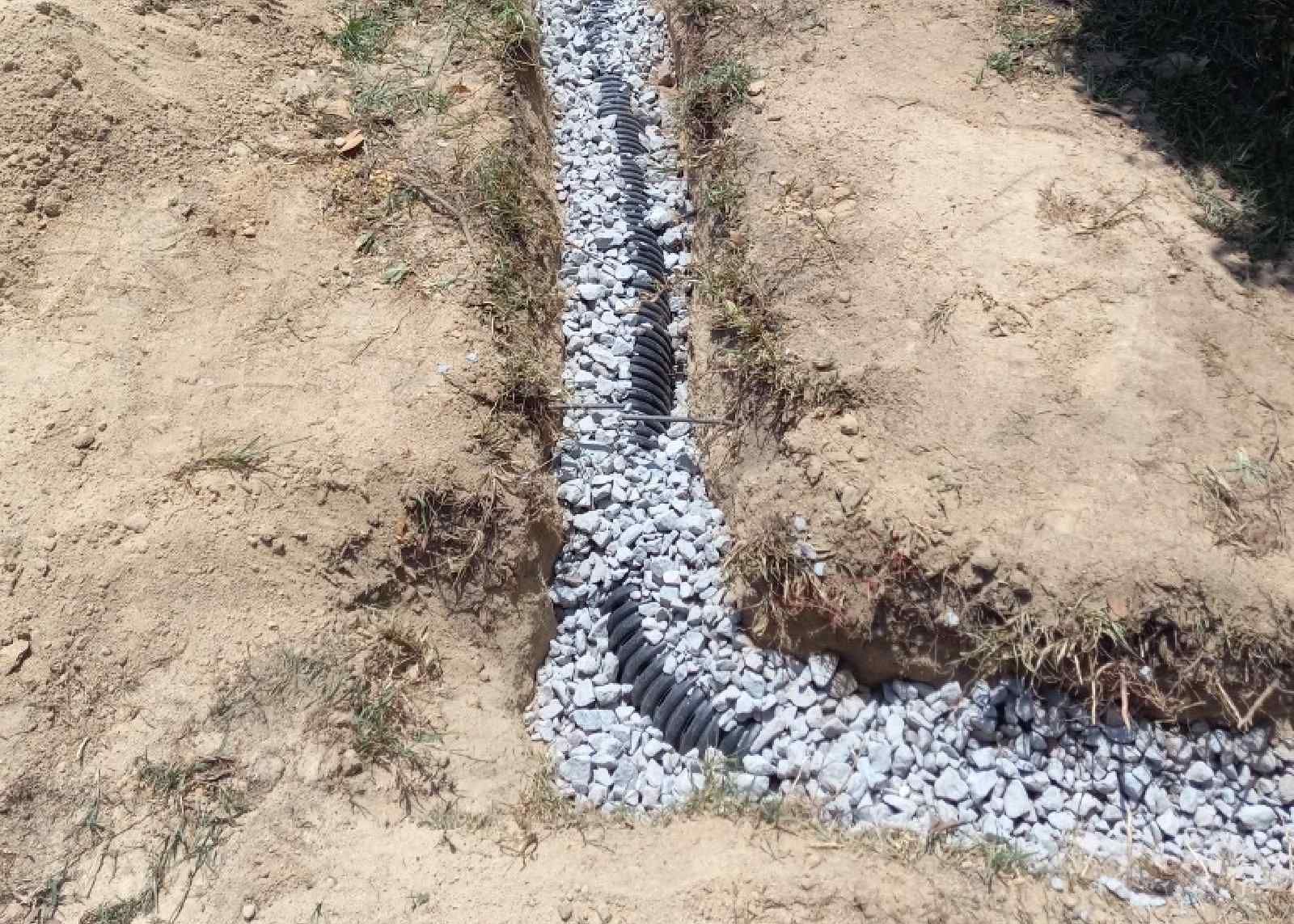 French Drain Trench With Some Rock Installed Around Pipe