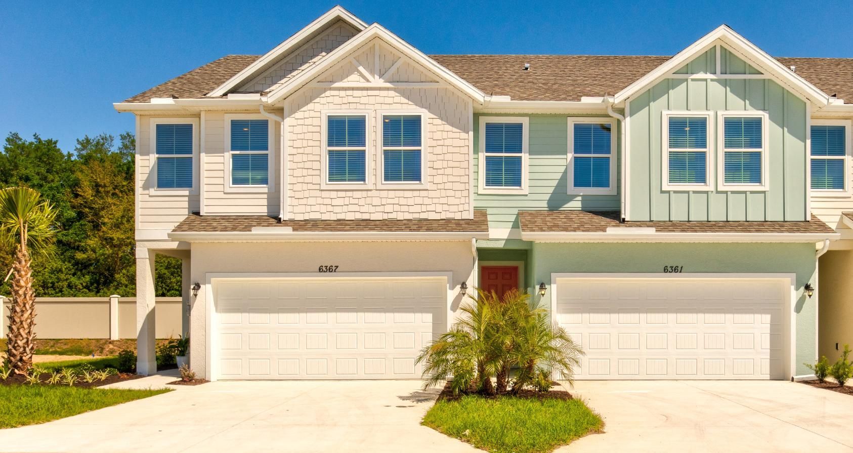 A row of houses with two garages on a sunny day.