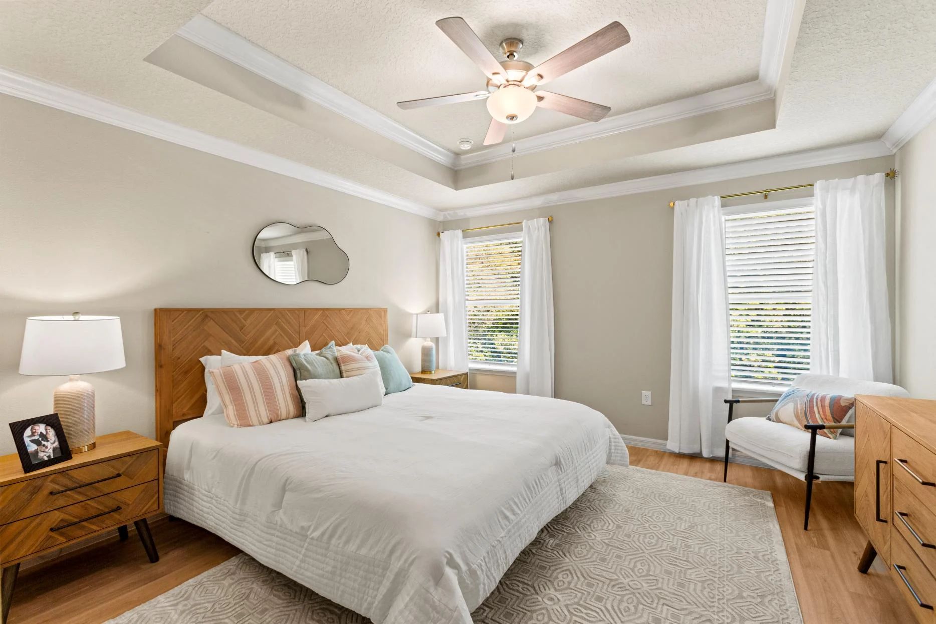 A bedroom with a bed , nightstand , chair and ceiling fan.