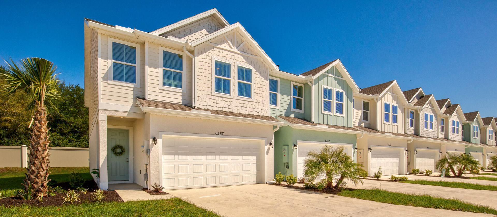 A row of white and blue houses with a palm tree in front of them.