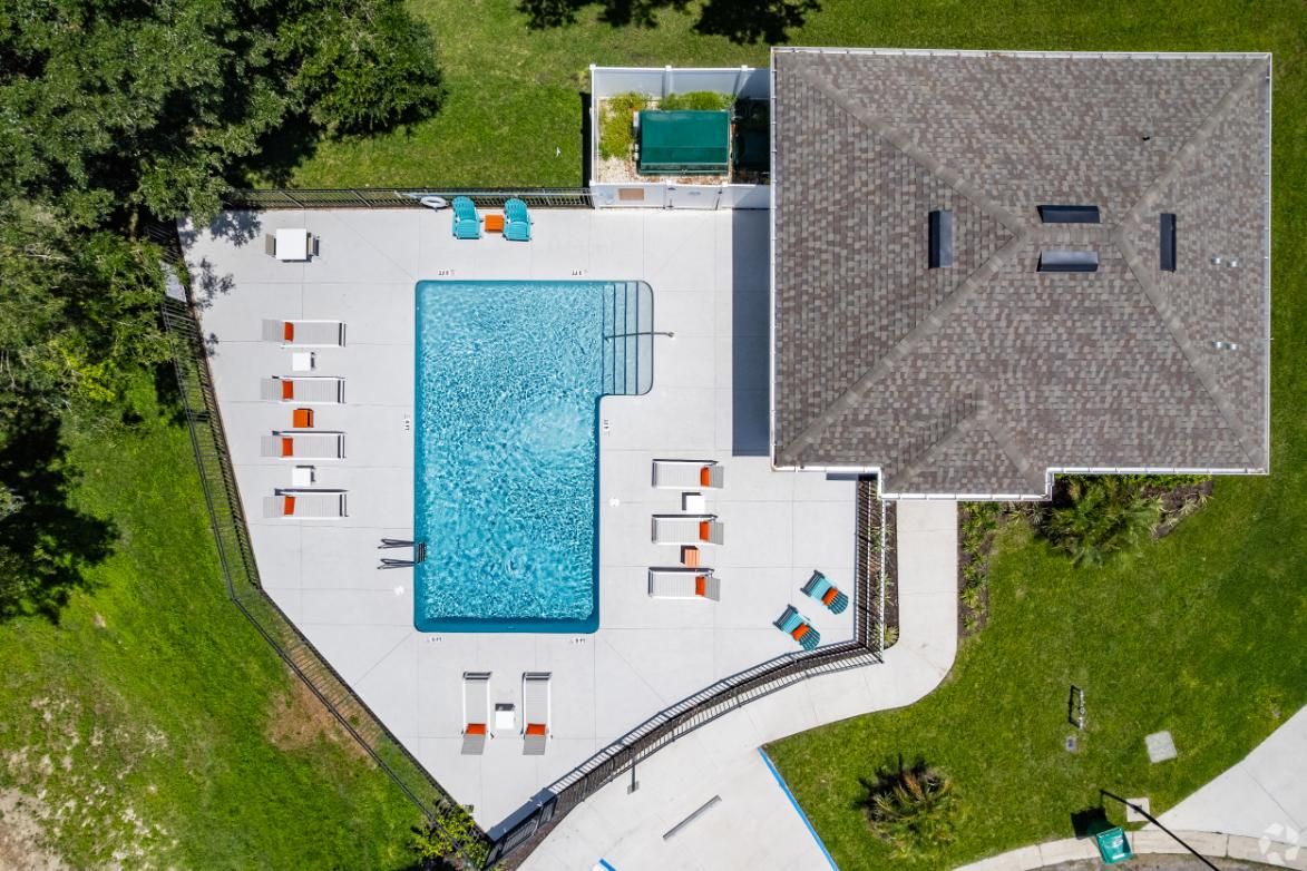 An aerial view of a swimming pool with a house in the background.