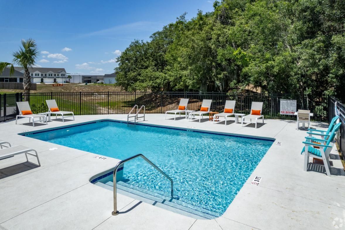 There is a large swimming pool with chairs around it.