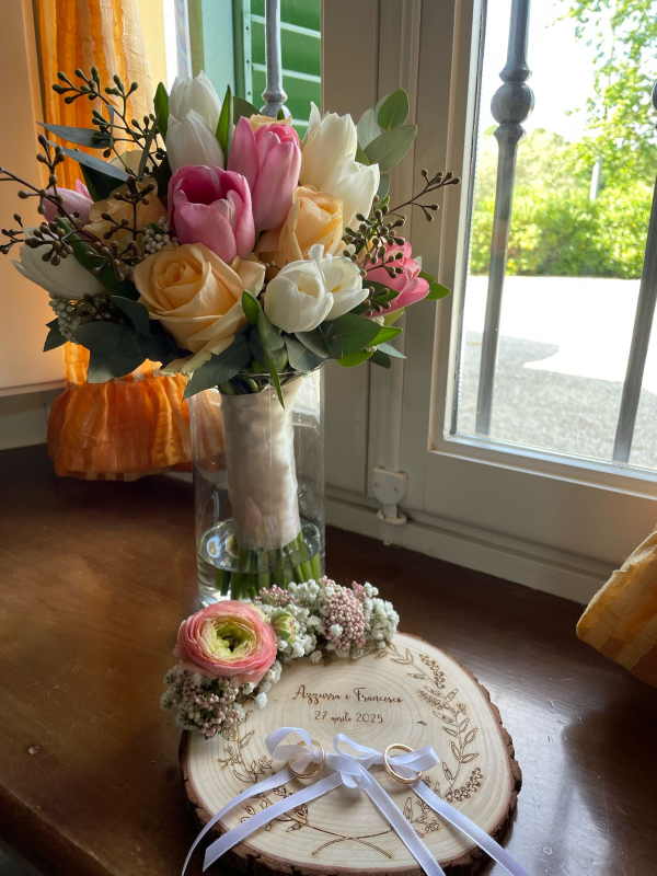 Bouquet da sposa con tulipani e rose, portafedi con anelli sul davanzale di una finestra.
