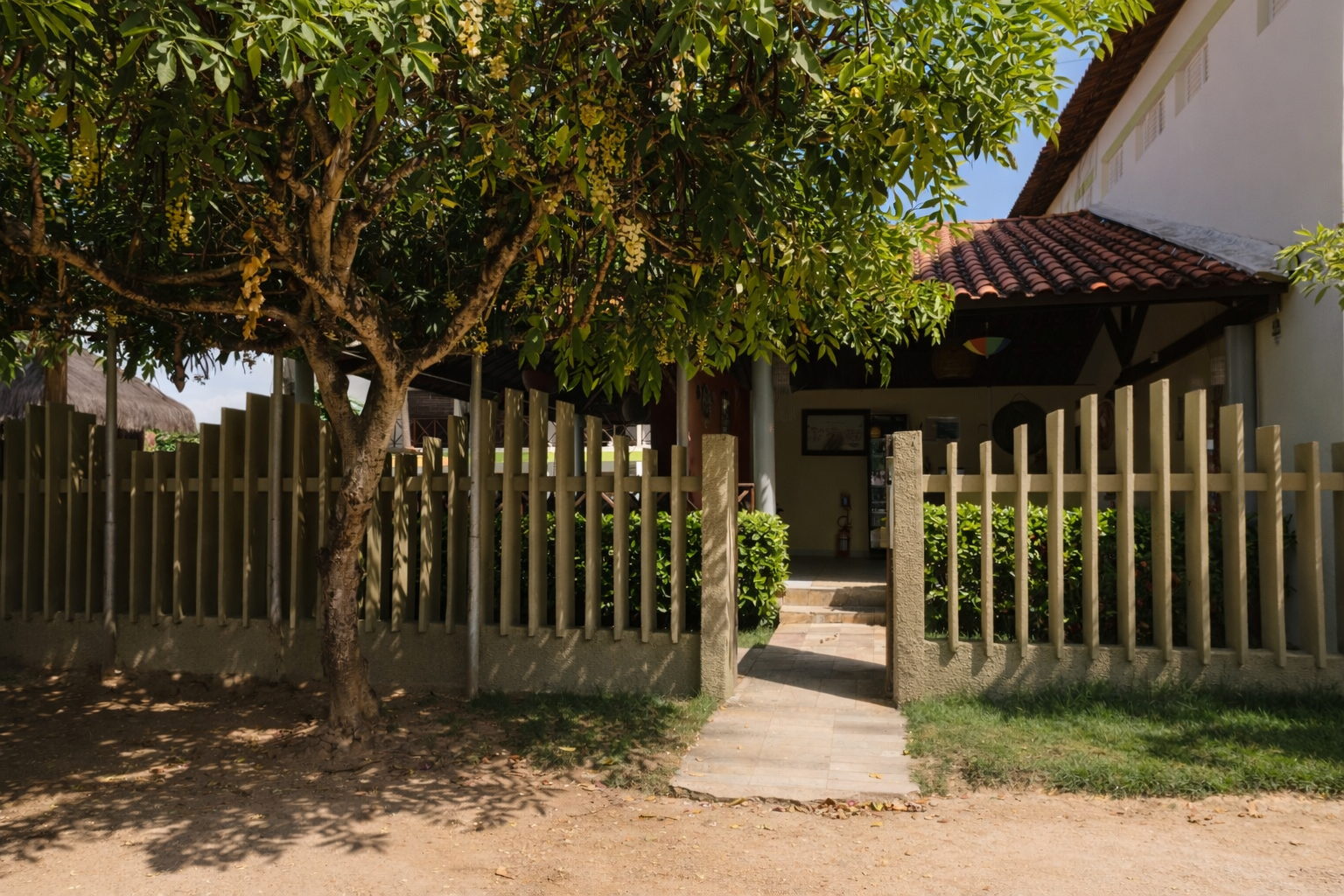 Uma casa com cerca e uma árvore na frente. Um caminho leva à entrada da varanda.