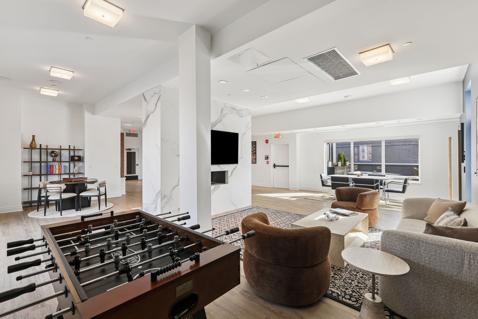 Modern lounge area with foosball table, seating, and a large TV.