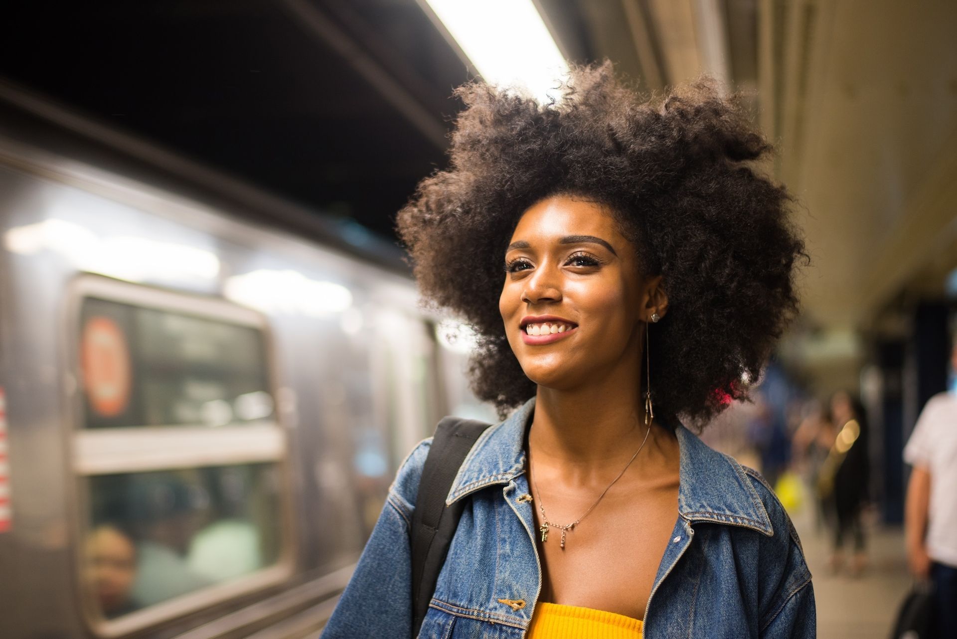 A woman is standing in front of a train at a subway station.
