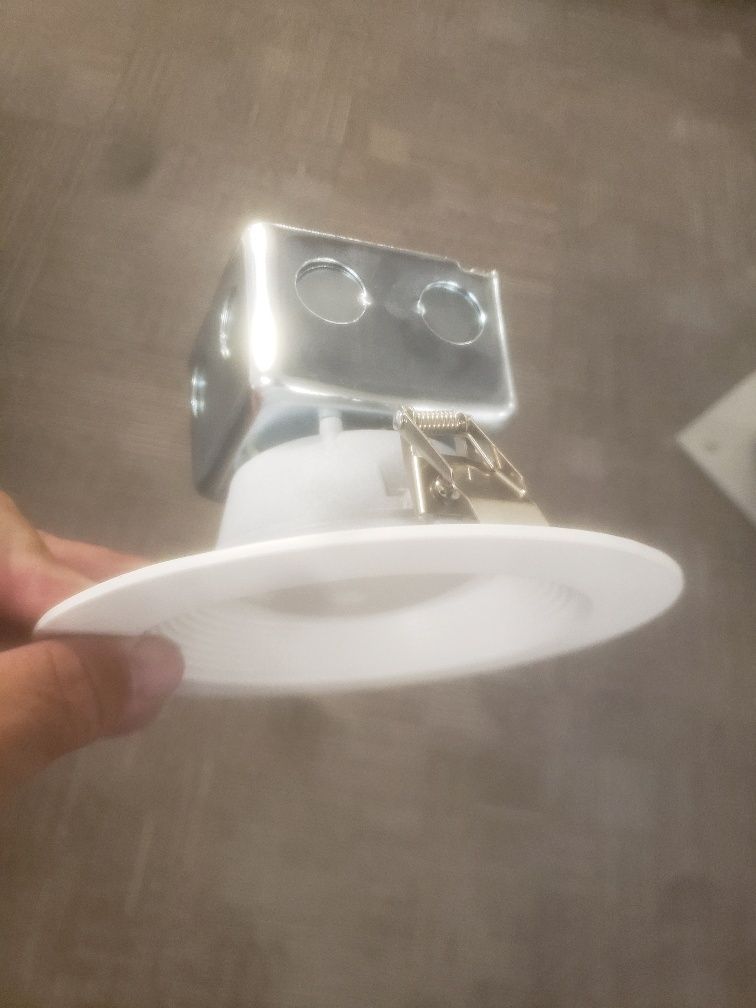 A person is holding a white light fixture in their hand.