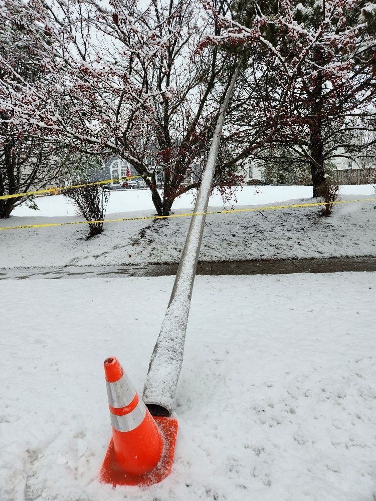 An orange and white traffic cone is sitting in the snow.