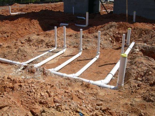 A bunch of white pipes are laying in the dirt