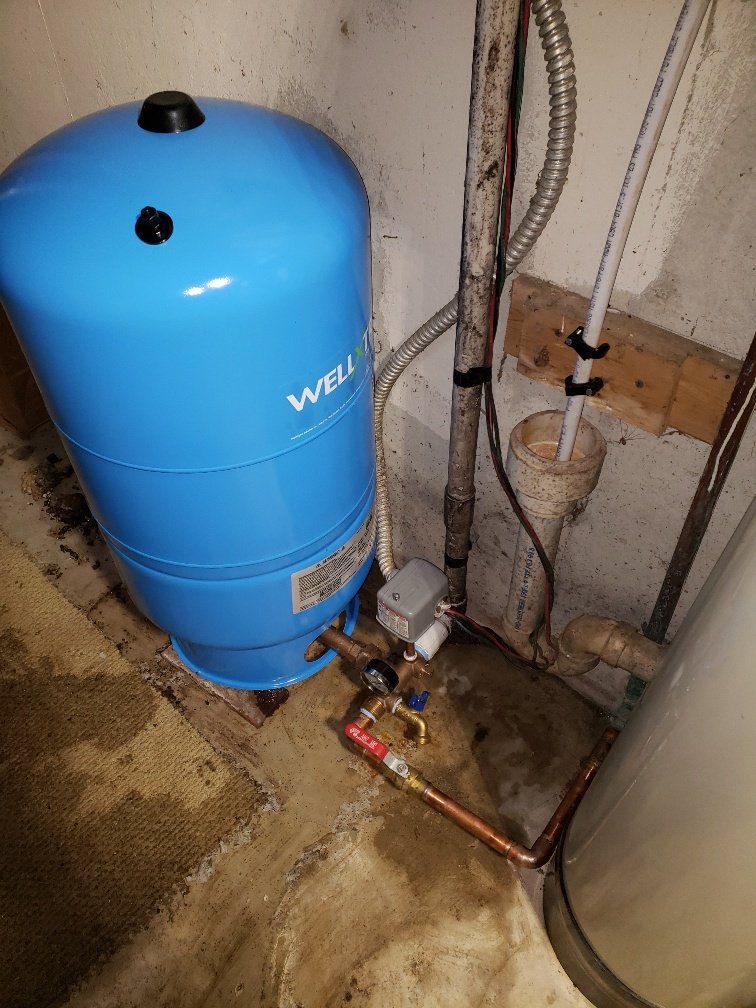 A blue water tank is sitting next to a water heater in a basement.