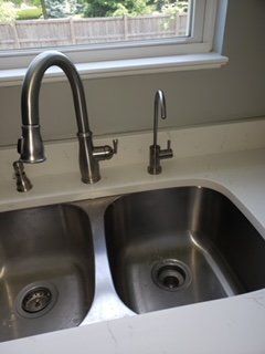 A kitchen sink with two stainless steel sinks and a faucet.