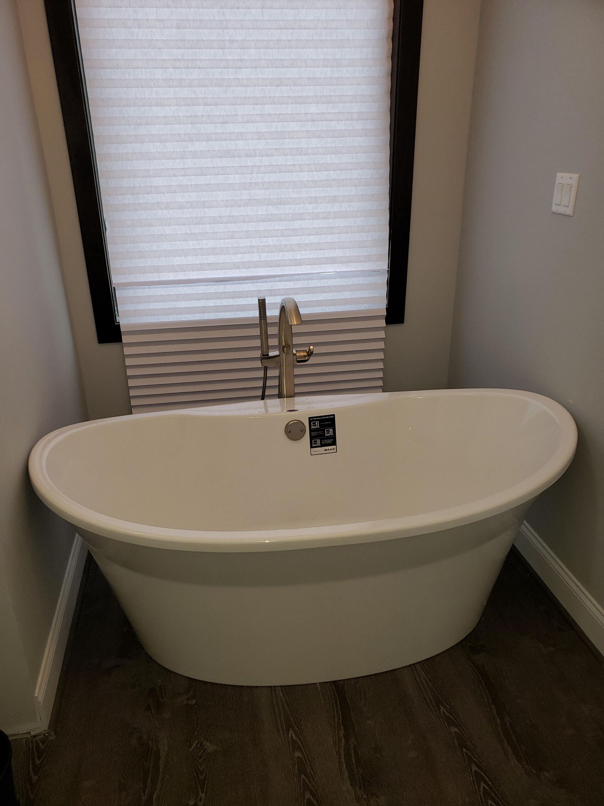 A white bathtub is sitting in a bathroom next to a window.