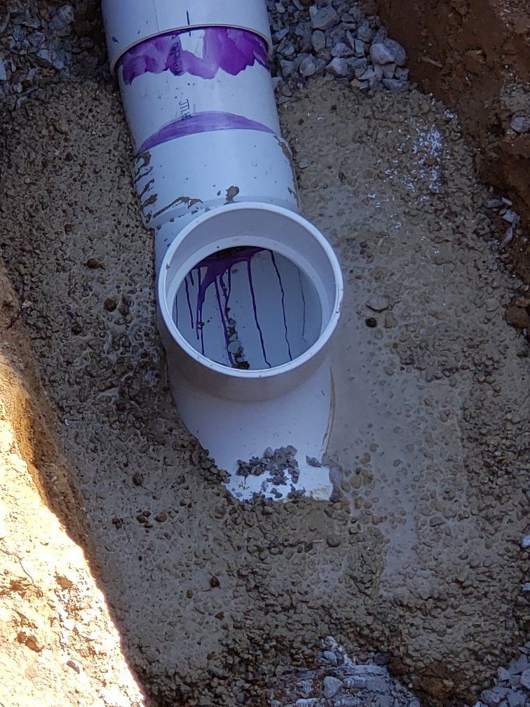 A white pipe is sitting in the dirt in a hole.