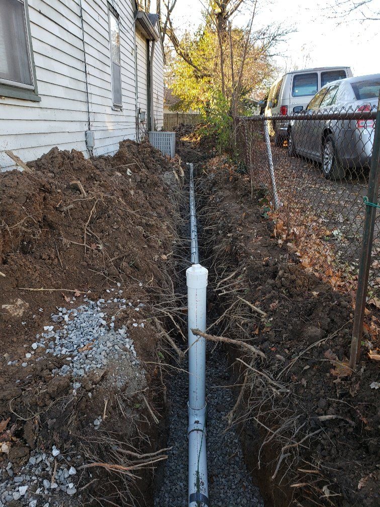 A pipe is being installed in the dirt next to a house.