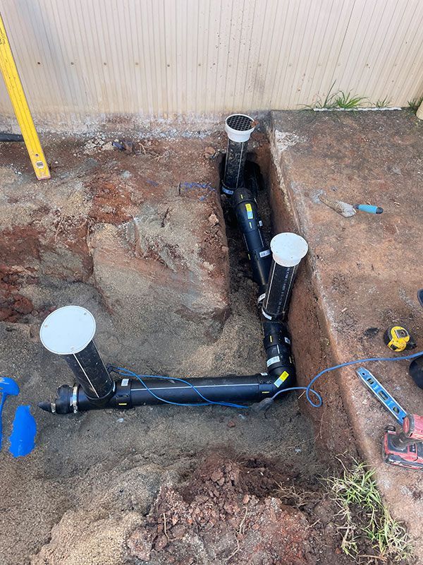 A Bunch Of Pipes Are Being Installed In The Dirt — Pertzels Plumbing In Wagga Wagga, NSW